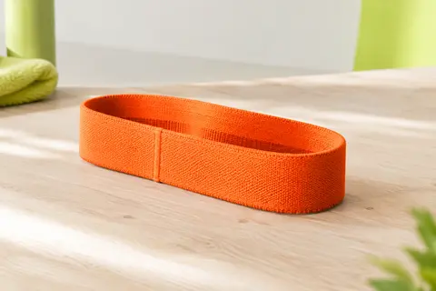 Mini-bande de résistance Flexvit orange en textile tissé, posée sur une surface claire.