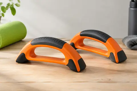 Paire de poignées de résistance orange à la forme arquée, posées sur une surface claire