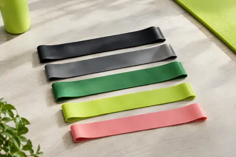 Cinq mini-bandes de résistance en latex naturel, de couleurs variées, posées sur un fond clair.