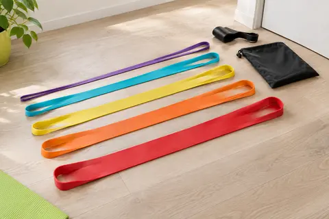 Cinq longues bandes élastiques en boucle de couleurs différentes, étendues côte à côte avec un ancrage de porte et un sac.
